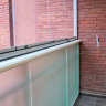 Парапет балкона закрыт матовым стеклом в прижимном профиле